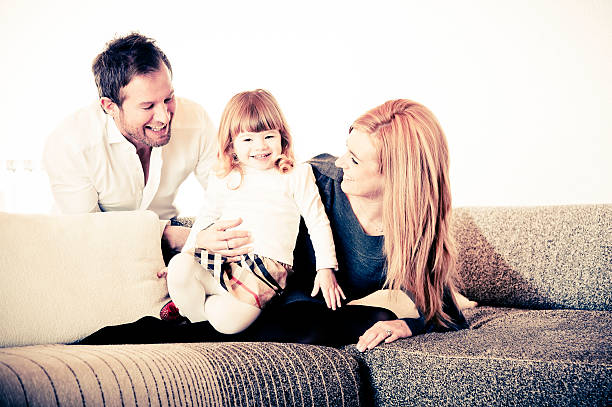 мать, отец и дочь на диван - three person family flash стоковые фото и изображения