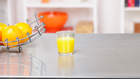 A portrait of a friut with oranges and orange juice on a kitchen worktop.