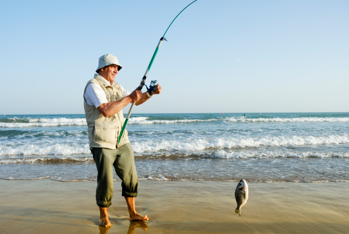 Senior man with a catch in a beach.Many more on fishing clicking on any image: