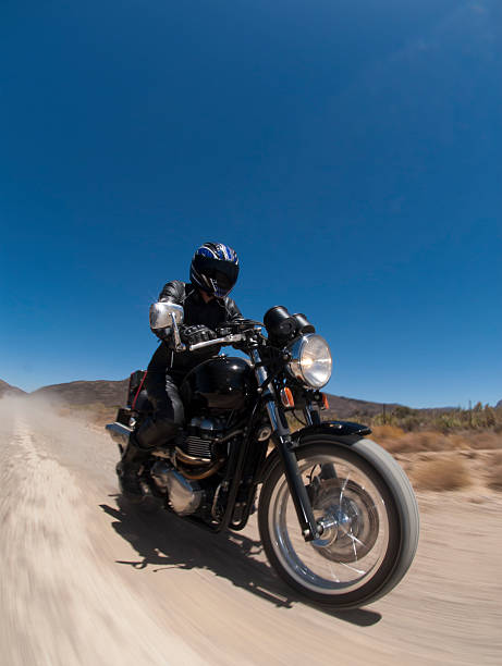 motorcyclist travelling on dirt road stock photo