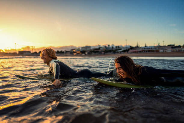 istock Two surfers with surfboard prepares to hit the waves at sunset. 1852155673