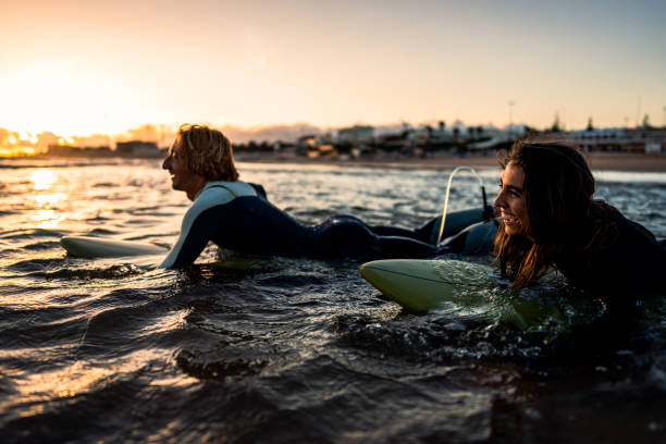 istock Two surfers with surfboard prepares to hit the waves at sunset. 1852155676