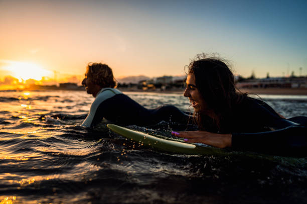 istock Two surfers with surfboard prepares to hit the waves at sunset. 1852155677