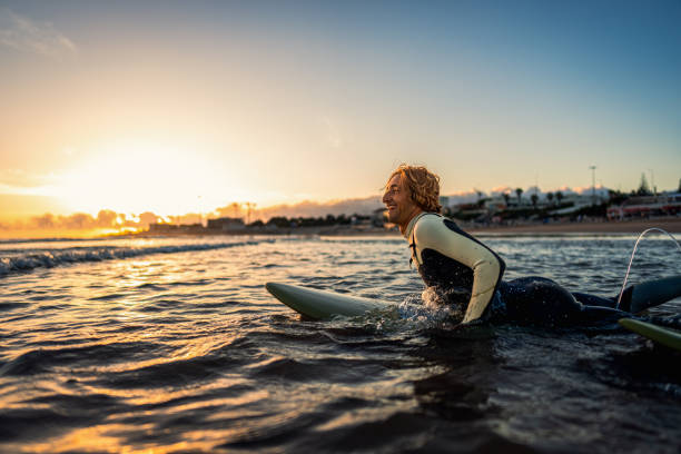 istock Two surfers with surfboard prepares to hit the waves at sunset. 1852155763