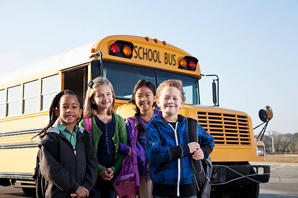 bambini in piedi fuori scuola bus - sc0536 foto e immagini stock
