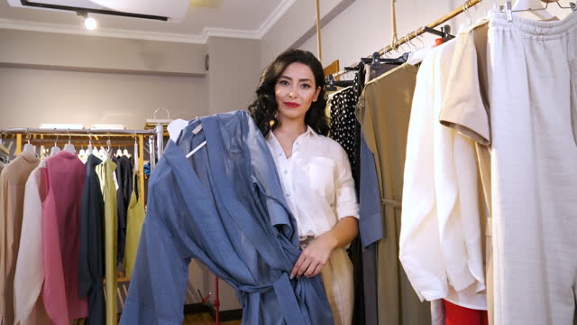 A young brunette woman chose a shirt on the rack