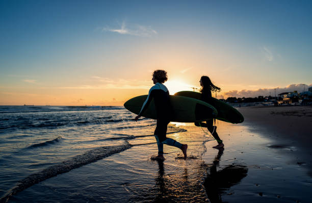 istock Two surfers with surfboard prepares to hit the waves at sunset. 1852158906