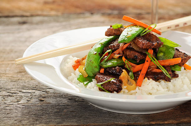 Stir fry meal including beef, peas, carrots, and rice stock photo