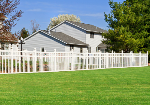 A white vinyl fence enclosing a back yard.