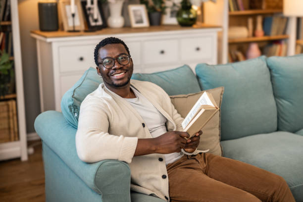 istock A man reading a book while sitting on the couch at home 1852163443