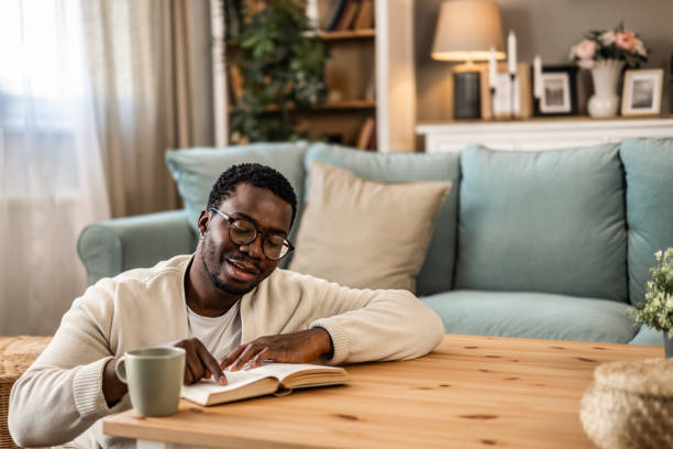 istock A smiling black man is reading a book and enjoying his new home 1852163779