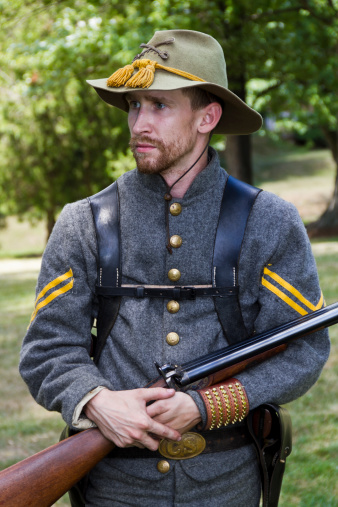 A man portraying a Confederate cavalry soldier during the American Civil War.  Rifle cradled in his arms.  Verticle orientation.