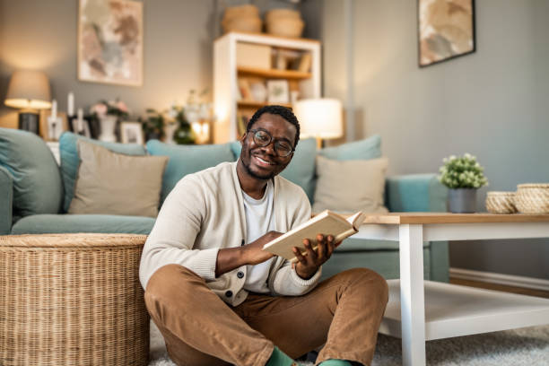 istock A smiling black man is reading a book and enjoying his new home 1852165384