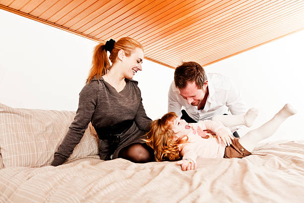 счастливая семья на кровати - three person family flash стоковые фото и изображения