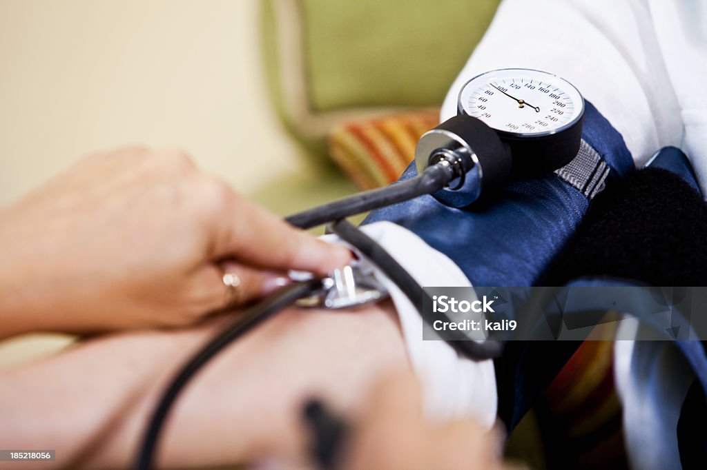Primer plano de enfermería de tomar la presión arterial del paciente - Foto de stock de 70-79 años libre de derechos