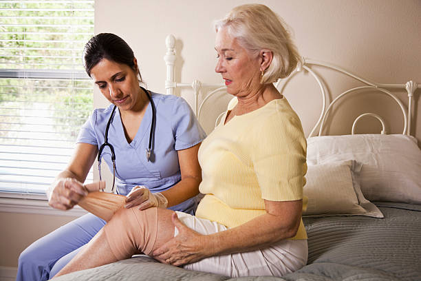 istock Healthcare worker bandaging patient's knee 185218464