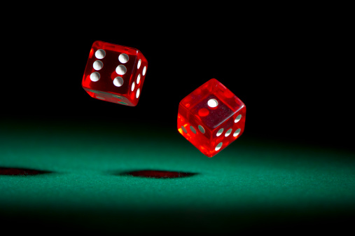 Red dice rolling on green felt.