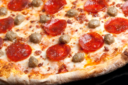 Pepperoni and italian sausage Pizza on black background
