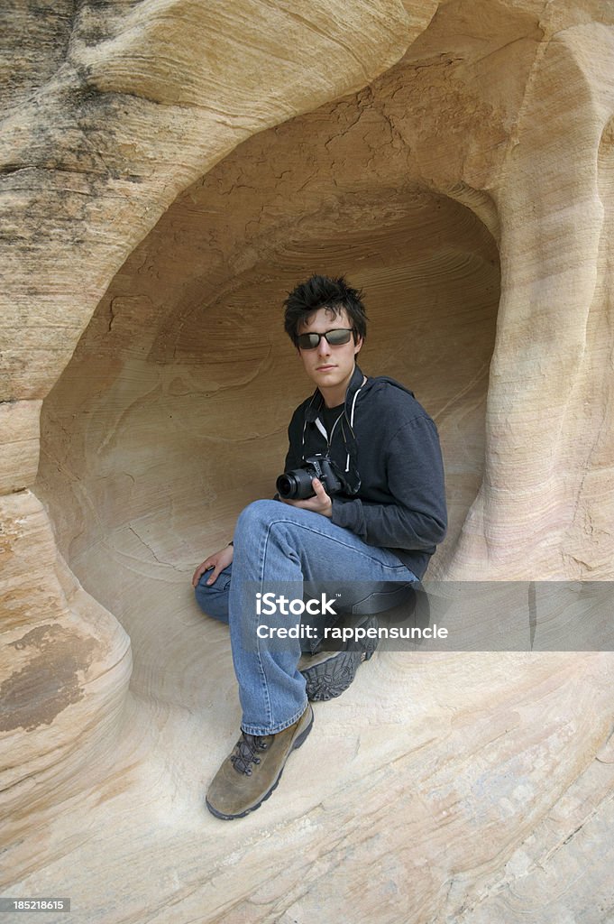 Jovem sentado na caverna de arenito - Foto de stock de Abraçar royalty-free