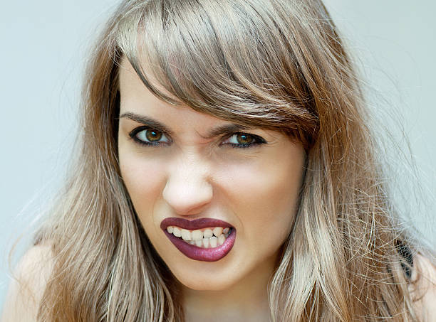 Furious Young woman baring her teeth, angry expression clenching teeth stock pictures, royalty-free photos & images