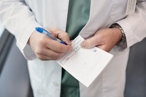 Close up of a doctor filling out a prescription Please click on an