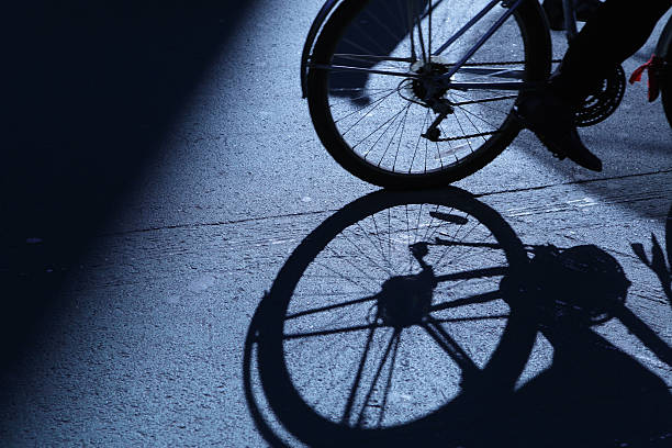 unrecognizable young adult man riding on his vintage bicycle at night in an empty square