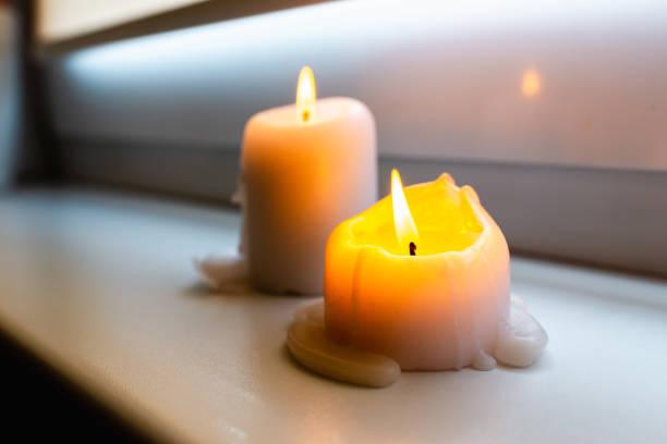 istock Two burning candles on windowsill.Two candles on a windowsill at home interior.Closeup. 1852194462