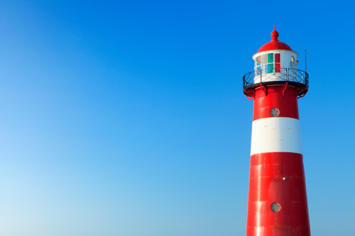 A bright red lighthouse and a clear blue sky.