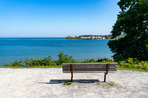 Empty wooden rest bench at sea shore by sunny summer day