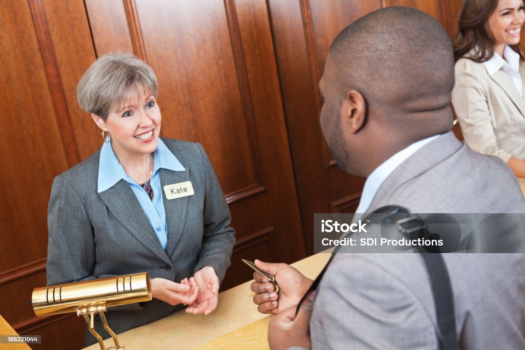 Friendly front desk lady helping hotel guest Friendly front desk lady helping hotel guest. African Ethnicity Stock Photo