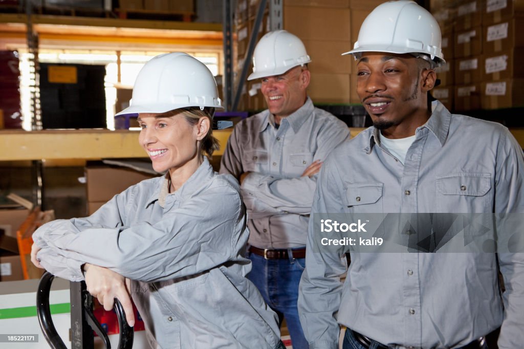 Diverse workers in warehouse Multi-ethnic workers in warehouse with pallet truck.  Focus on woman (40s) and African American man (20s). 20-29 Years Stock Photo