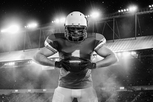American football player on stadium before game. Template for a sports magazine on the theme of American football with copy space. Black and white
