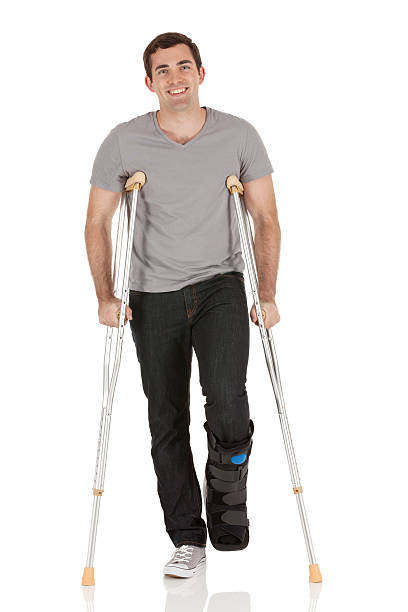 heridas hombre caminando con la ayuda de crutches - physical impairment smiling front view looking at camera fotografías e imágenes de stock