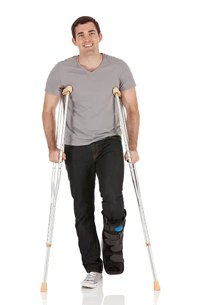 Photo of Injured man walking with the help of crutches