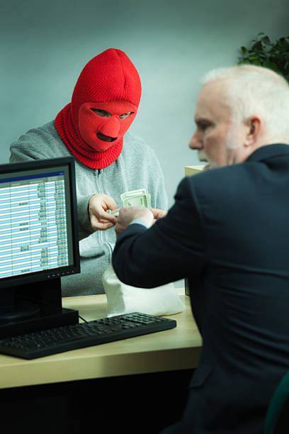 istock Masked Robber Robbing a Retail Bank Counter with Teller Vt 185222658
