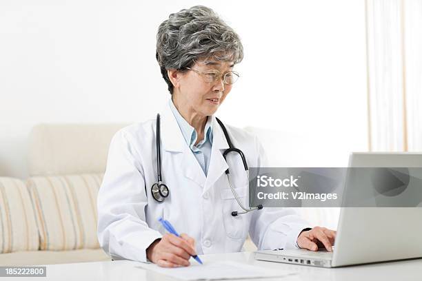 Doctora Usando Computadora Portátil Llenado Forma Foto de stock y más banco de imágenes de Doctor - Doctor, Ordenador portátil, 55-59 años