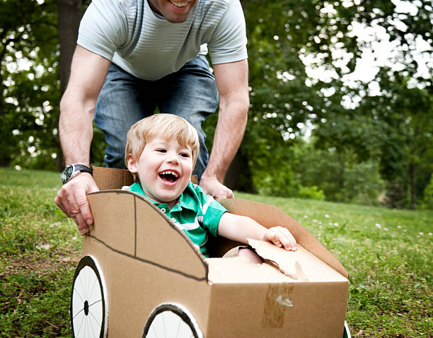 istock Little boy being pushed by his dad in a cardboard car 185223176