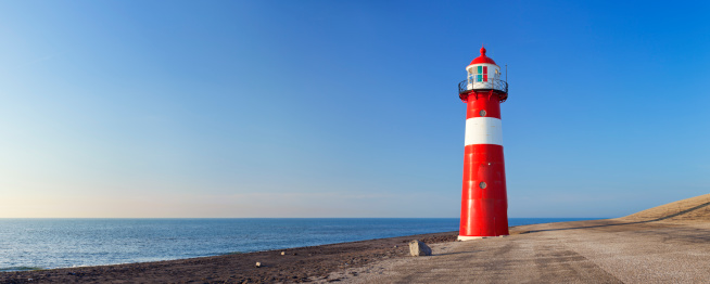 A bright red lighthouse and a clear blue sky. A seamlessly stitched panoramic image.