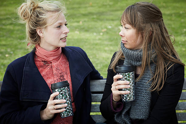 istock Two female college students sitting in a park with coffee 185223865