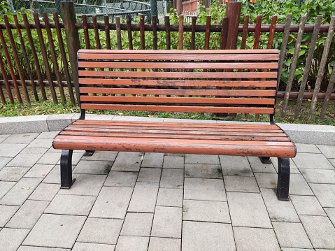 Johor Bahru, Malaysia, December 11, 2023\n\nBehind the brown-colored chair, there is a wooden fence, and the area appears neat with no litter in sight.