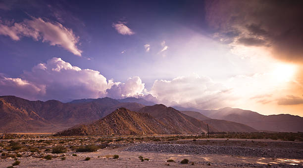 Dramatic Palm Springs Landscape Flat desert quickly gives way to steep dry hills in the dusty Southern California desert, set against a dramatic sky. desert wash stock pictures, royalty-free photos & images