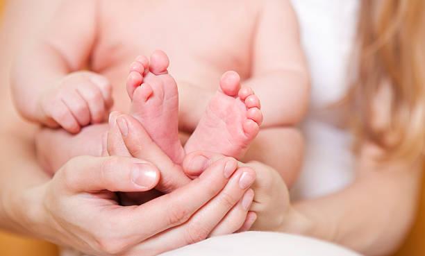 istock Newborn baby`s feet in mother`s hand 185225312