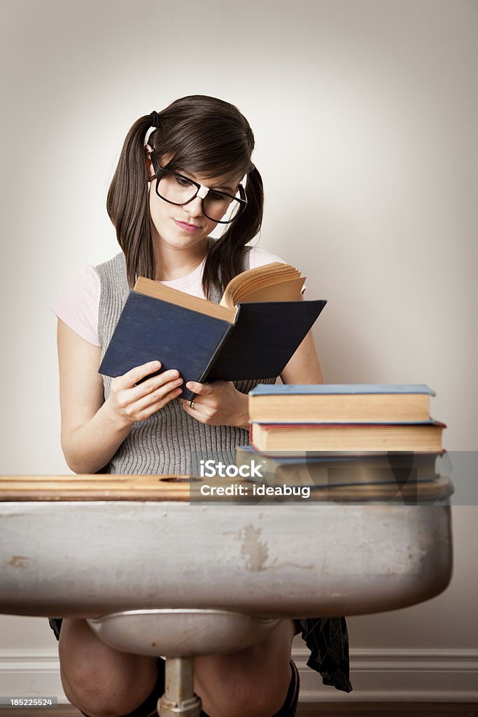 Nerdy молодая женщина Студент чтения книги в школе стол - Стоковые фото 20-29 лет роялти-фри