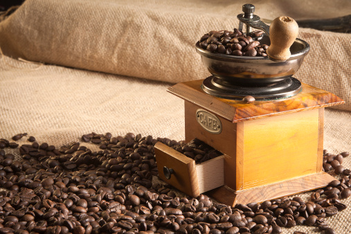 Coffee grinder and coffee beans put on old wooden with white background.