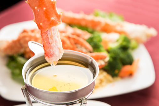 A delicious looking meal of king crab being dipped in butter. Shallow depth of field is intentional