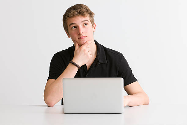 pensive student at working on laptop - alleen één tienerjongen stockfoto's en -beelden