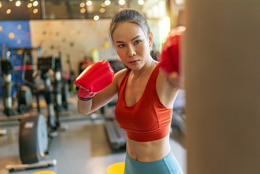 Asian Woman Engaged in Boxing Training at an Indoor Fitness Gym Club