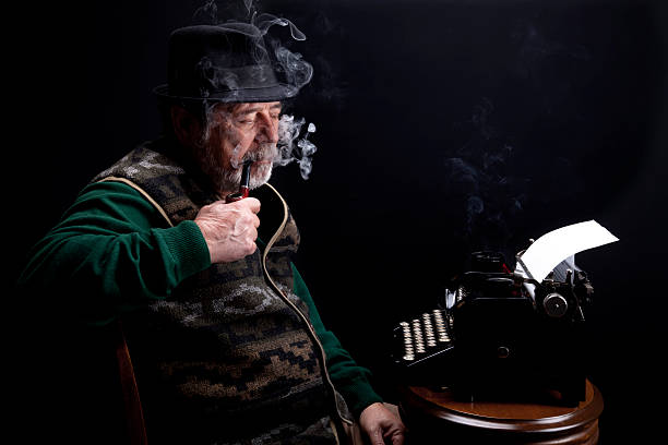 istock senior man smoking pipe with looking vintage typewriter 185226712