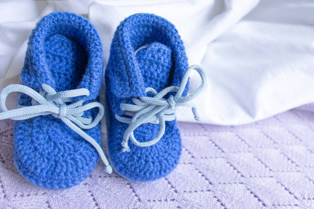Blue booties-socks on a purple knitted plaid for newborns