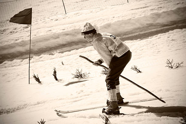 Old Style skiing competitor in action "Vintage black and white toned photography of a young skier using equipment from 1950's. One ski pole only.Slovenia, Europe." back country skiing photos stock pictures, royalty-free photos & images